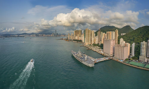 High angle view of buildings by sea against cloudy sky