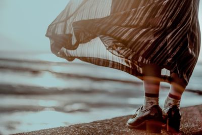 Low section of woman on beach against sky