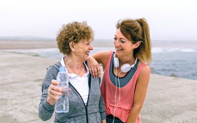 Mother and daughter standing on pier against sky