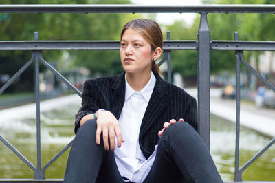 Young woman looking away while standing on railing