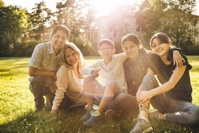 Portrait of smiling family sitting on grassy field at park