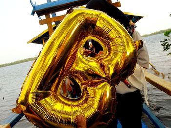 Close-up of yellow wheel by sea against sky