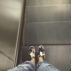 Low section of woman standing on escalator