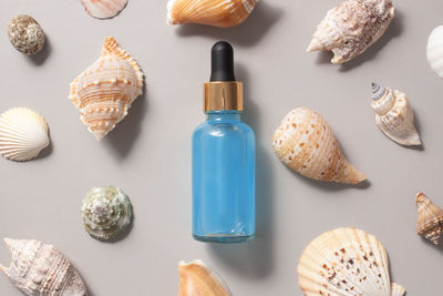 A glass bottle with liquid oil to moisturize. essence for skin care, seashells background flatly.