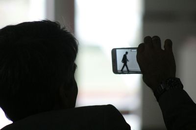 Rear view of man using mobile phone