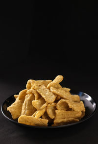 Close-up of bread in bowl against black background