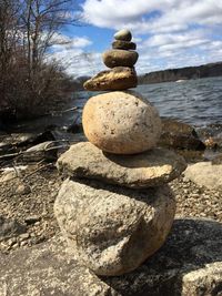 Close-up of stone stack on shore against sky