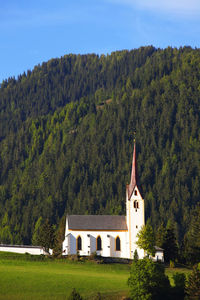 Chapel against green mountain against blue sky