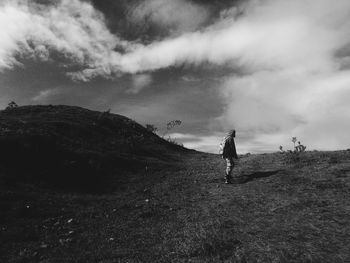 Rear view of man standing on mountain against sky