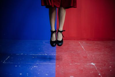 Low section of ballerina jumping over red and blue floor