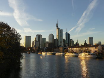 Scenic view of river by buildings against sky