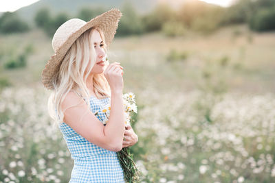 Beautiful woman smelling flower standing on field