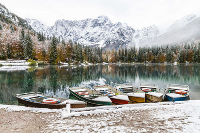 Boats moored in lake against snowcapped mountains