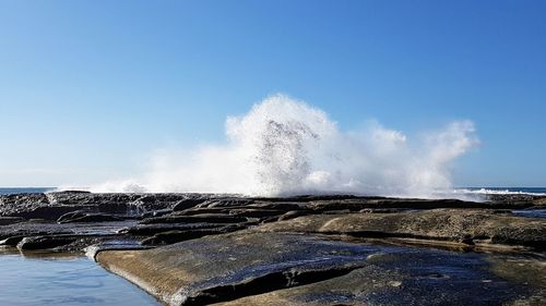 Water splashing in sea against clear blue sky