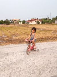 Full length of boy riding bicycle on road against sky