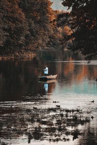 Man in boat on lake against trees