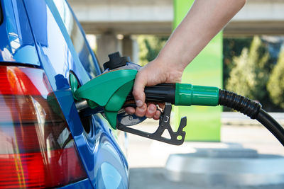 Cropped of person holding gas pipe at gas station