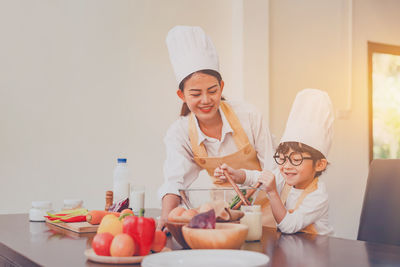 Smiling woman assisting son preparing food at home