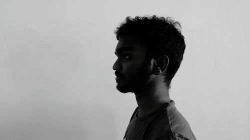 Profile view of young man standing by wall