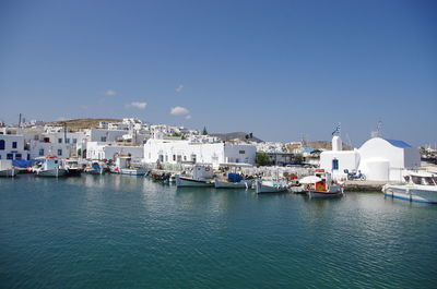 Sea by cityscape against clear blue sky