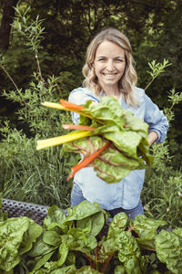 Portrait of a smiling young woman holding plants