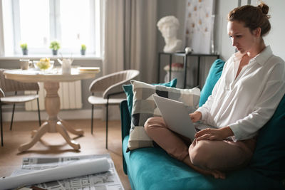 Serious designer using laptop on couch