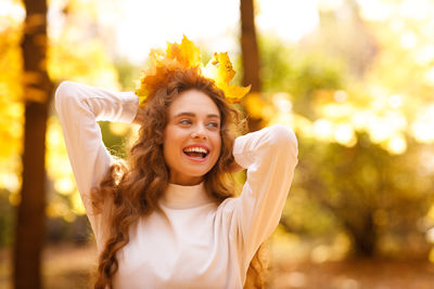 Portrait of young woman standing against trees