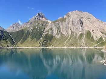 Scenic view of lake and mountains against blue sky