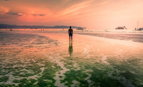 Man standing on beach against sky during sunset