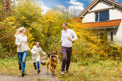 Family running with dog during autumn