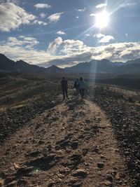 Rear view of men walking on mountain against sky