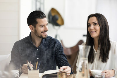 Smiling business people talking during meeting at table in office