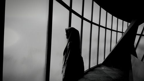 Side view of woman standing by window