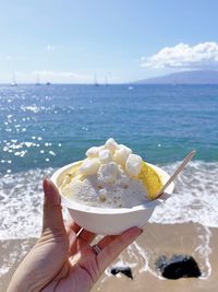 Midsection of woman holding ice cream against sea