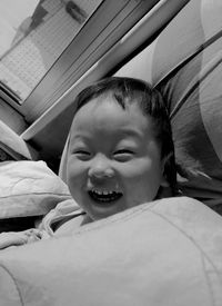 Portrait of smiling boy lying on bed at home