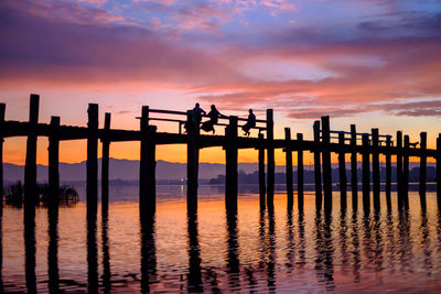 Silhouette man standing on pier by sea against sky during sunset