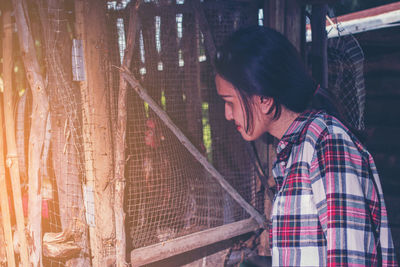 Young woman looking at chicken bird at farm