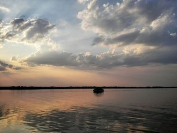 Boats in sea against cloudy sky