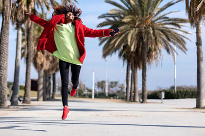 Full length of young woman jumping on street