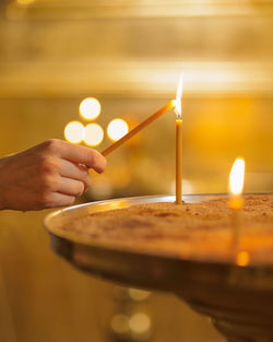 Cropped hand holding lit candle