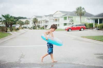 Full length of boy skateboarding on road in city