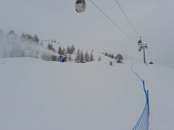 Close up of ski lift durino a snowfall with snow cannons belinda it ski on snow covered landscape