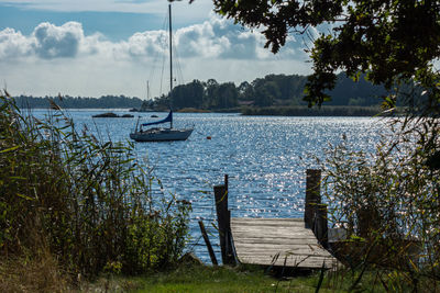 Sailboat sailing in river against sky