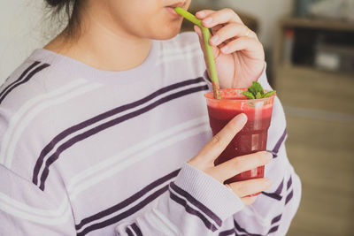 Midsection of woman drinking juice