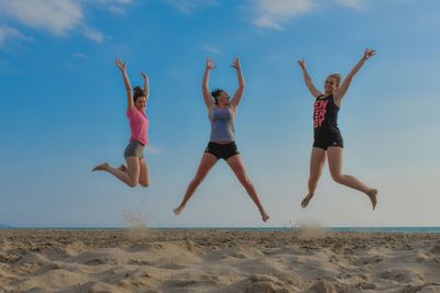 Full length of young woman jumping on beach