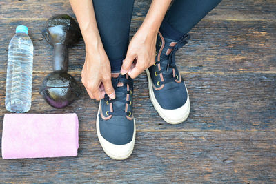 Low section of woman tying shoelace on table