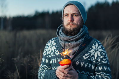 Portrait of man holding lit candle against blurred background