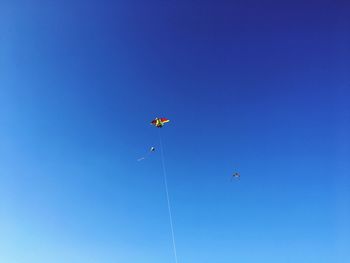 Low angle view of kite against clear blue sky