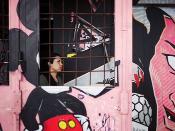 Woman standing by window of building