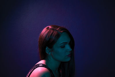 Portrait of young woman against blue background